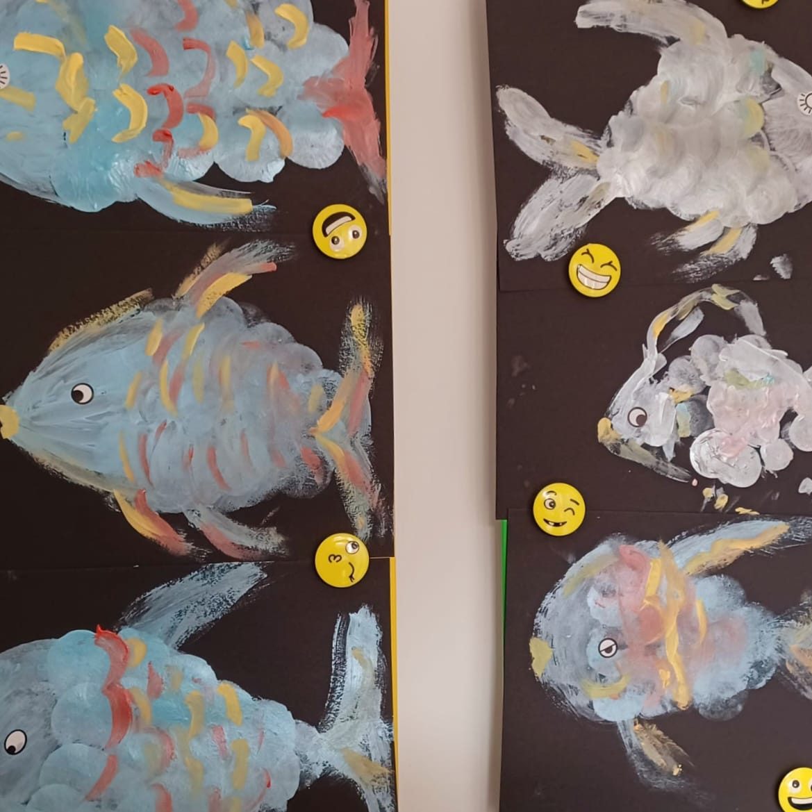 Bunte, gemalte Fische auf dunklem Hintergrund mit gelben Smileys.